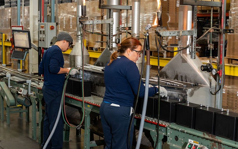 Lead battery manufacturing employees filling new lead batteries with raw materials from sustainable recycling. Lead battery manufacturing employees filling new lead batteries with raw materials from sustainable recycling.