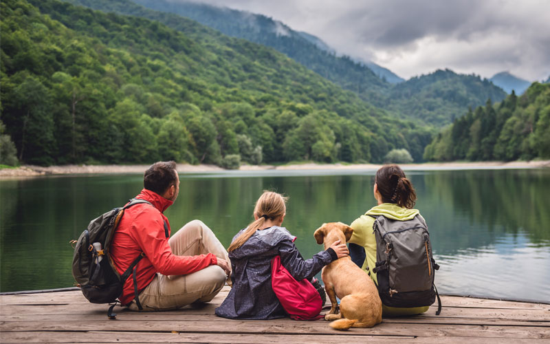 Family sitting on a doc looking at a lake and mountains representing environmental health.