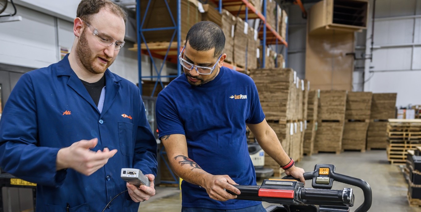 Lead battery recycling employee shadowing another worker in a supervisory role mentorship program.