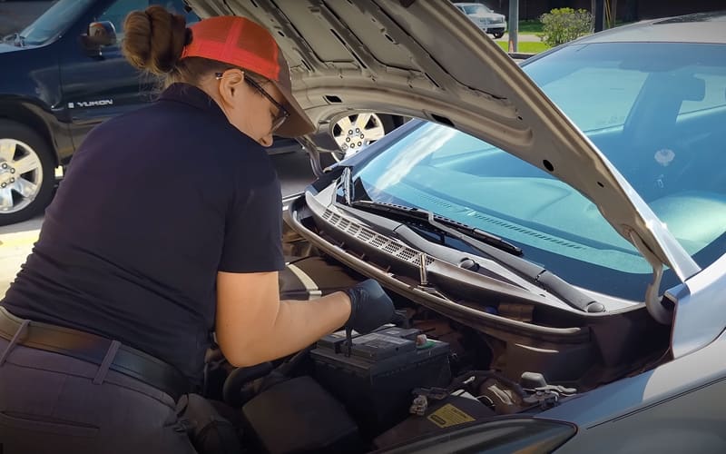 Woman removing a used car battery from her vehicle to turn it in for recycling. Woman removing a used car battery from her vehicle to turn it in for recycling.
