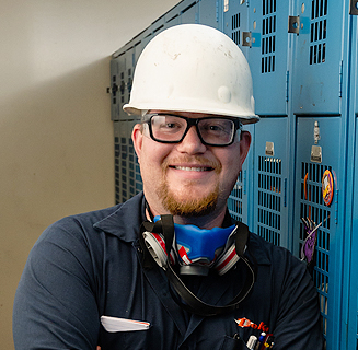 Battery recycler employee smiling in a lead battery recycling facility.