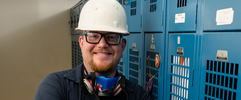 Battery recycler employee smiling in a lead battery recycling facility. locker room.