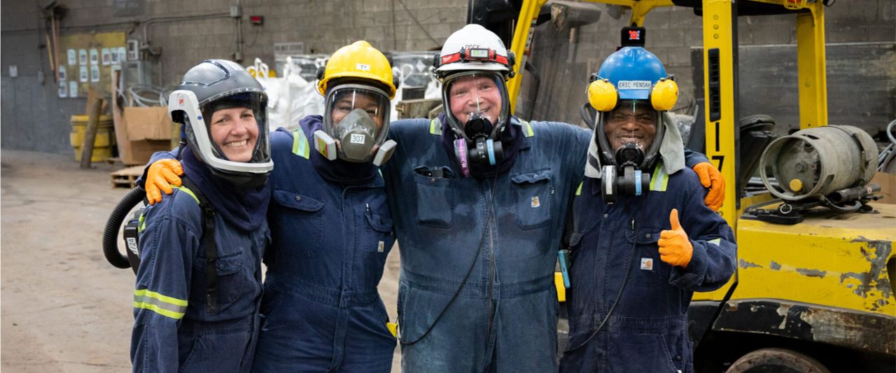 Four lead battery recycling workers outside together.
