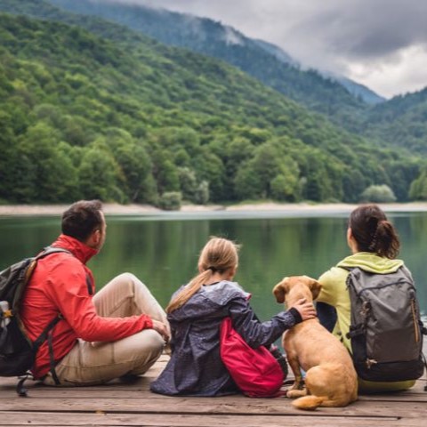 Family sitting on a dock looking out at a lake and mountains, illustrating environmental health.
