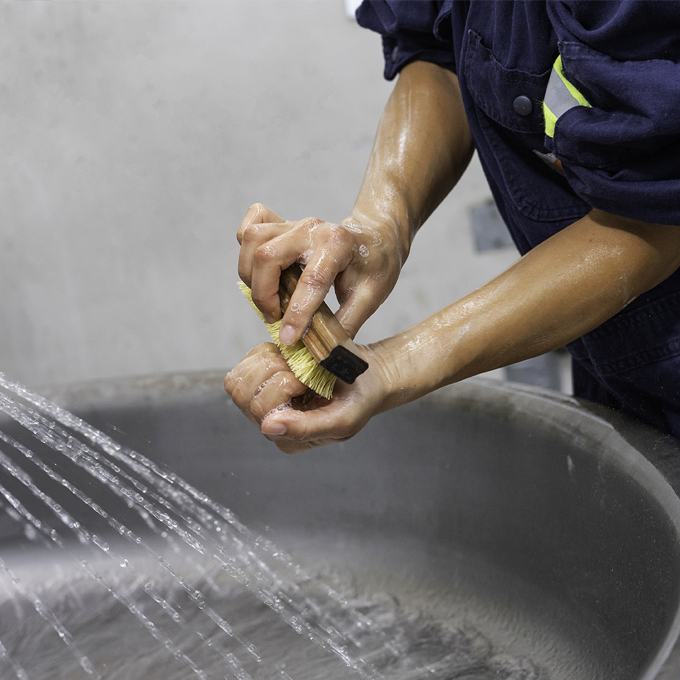 Lead battery recycling employee scrubbing her nails to reduce lead exposure.