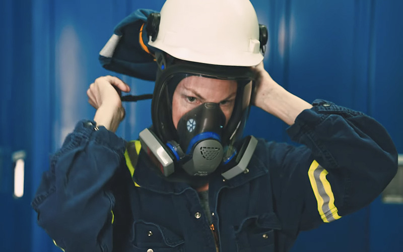 Lead battery recycling worker putting on PPE, part of the stringent environmental, health, and safety regulations in the U.S.