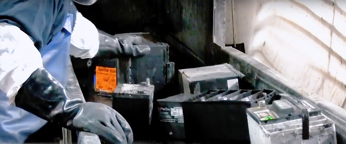 Worker sorting lead batteries to identify and remove lithium batteries from the recycling stream.